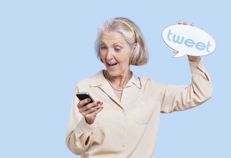Senior woman in casuals using social media on her Smartphone against blue background