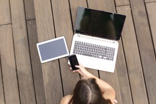 Woman using multiple devices phone laptop and tablet